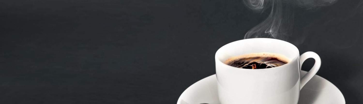 eine weiße Kaffeetasse mit Untertasse und Löffel. Schwarzer duftender Kaffee - Martina Wagner Immobilien